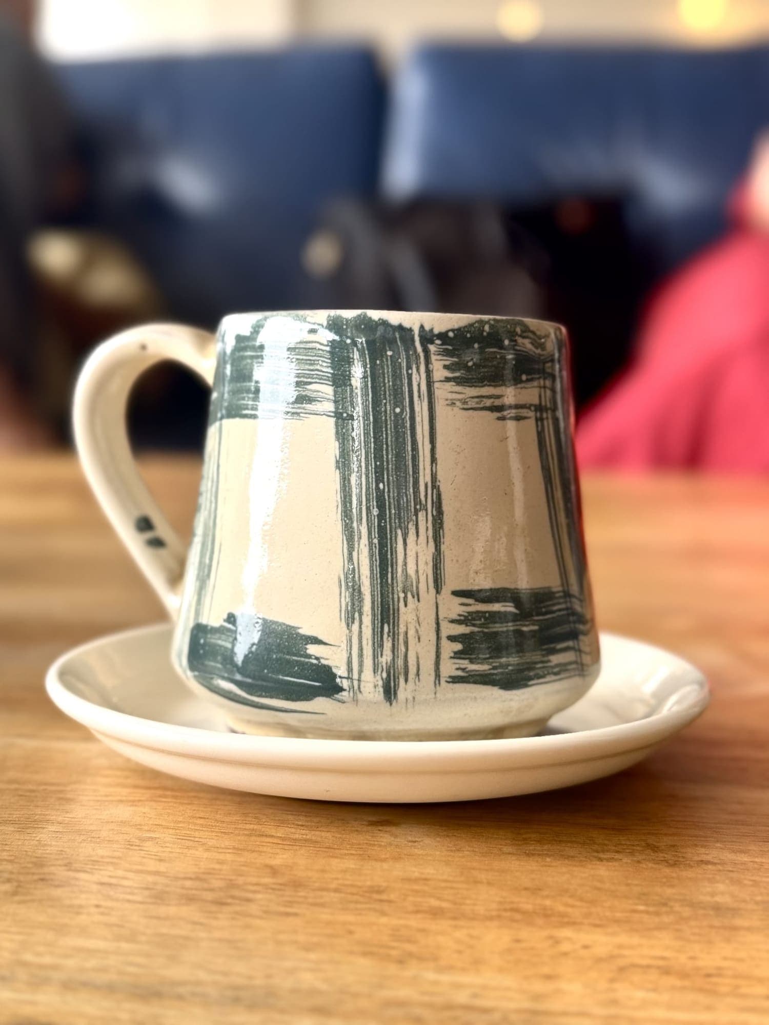 Tazza bianca con larghe pennellate grigio-verdi, su piattino.