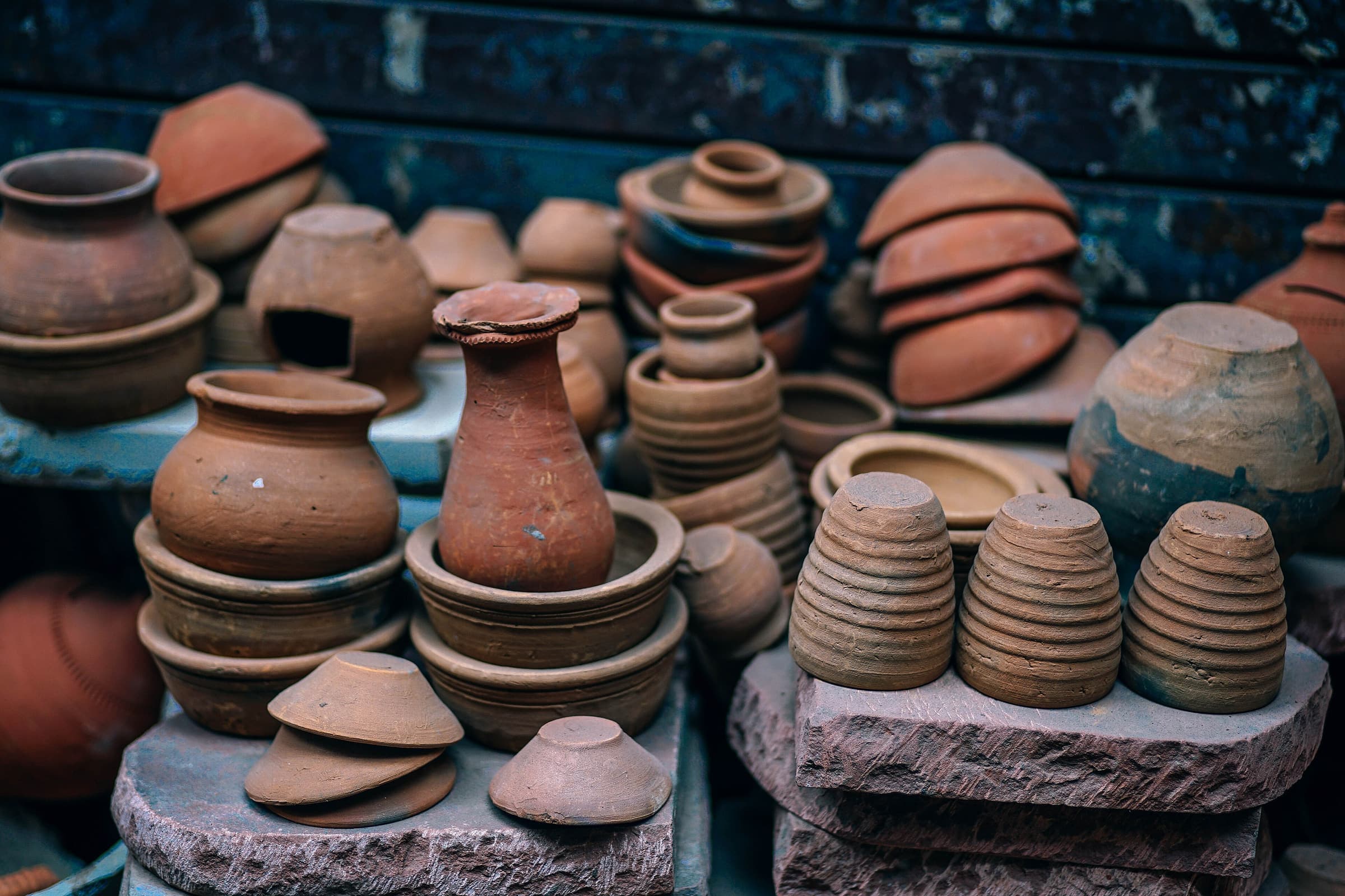 Molti oggetti in terracotta nuda, coperchi impilati e piccoli vasi.